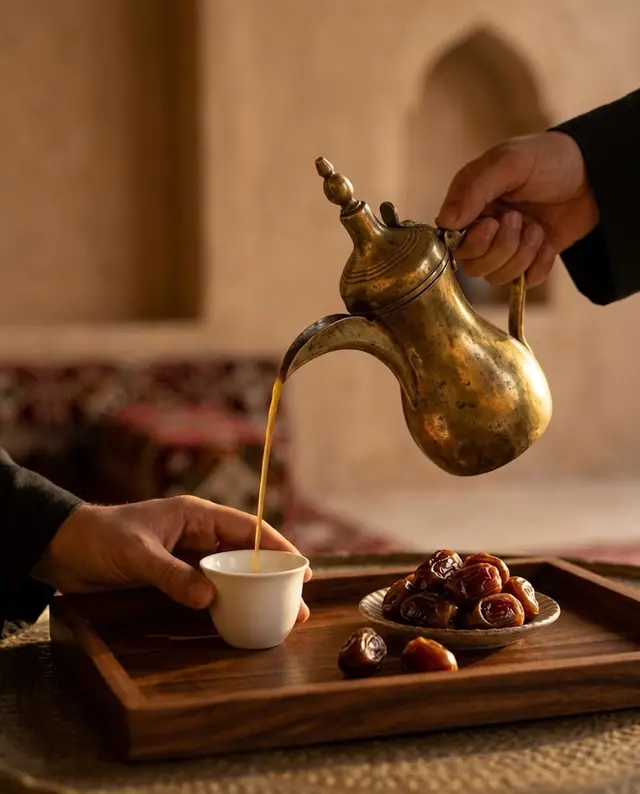 صب القهوة السعودية من الدلة في فنجان بجانب تمر
